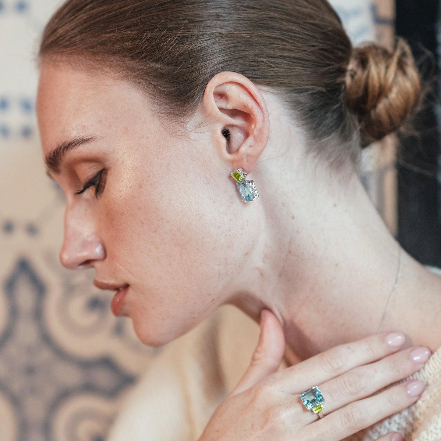 London-made luxury custom gold jewellery – Model demonstrating the wear of the 9ct Yellow Gold Octagon Ring in Peridot and Blue Topaz and the 9ct Yellow Gold Octagon Gold Drop Earrings in Peridot and Blue Topaz – Andalusian Collection, Augustine Jewellery, British Jewellers, Gemstone Jewellery, Luxury Jewellery London.